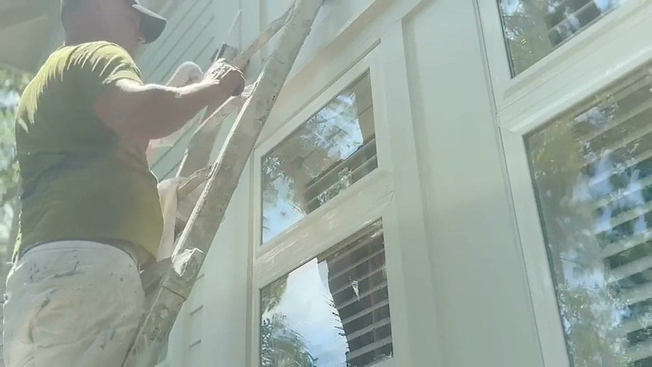 Close-up of a Cucol LLC crew member working at the windows of a white home