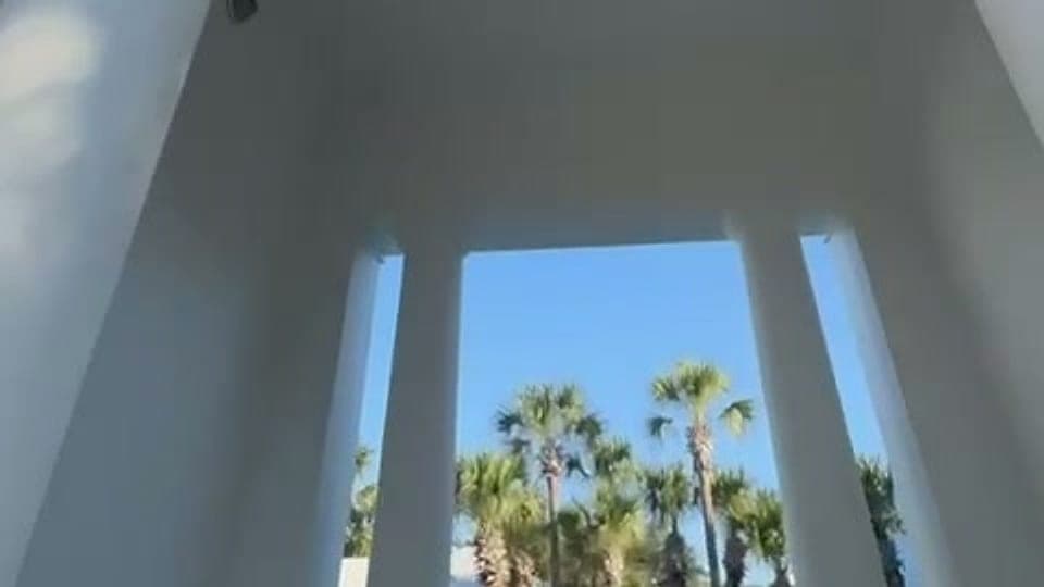 White pool cabana columns framing palm trees on the Emerald Coast