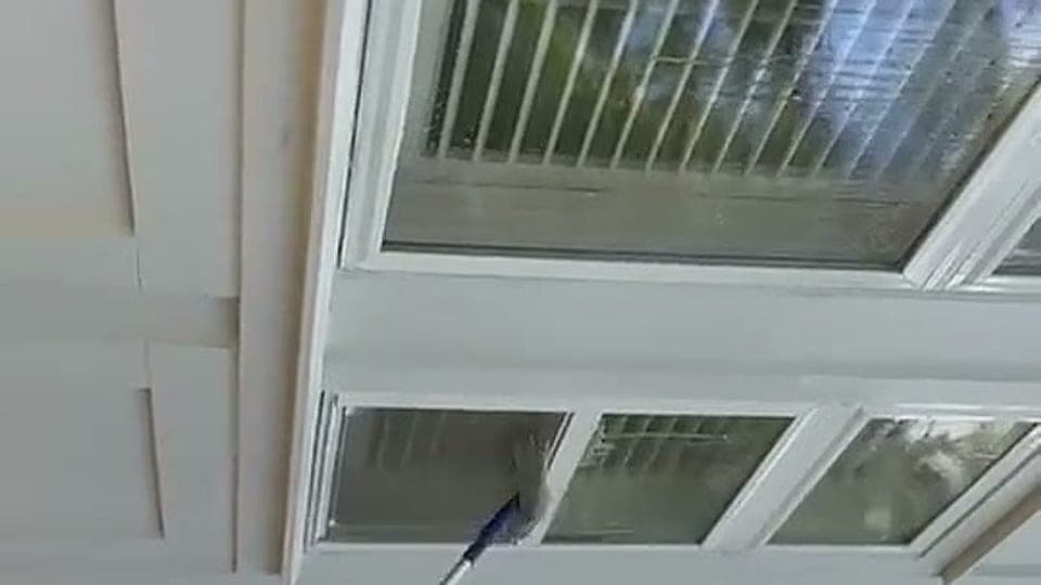 Soft washing windows and soffits from the ground on a white home